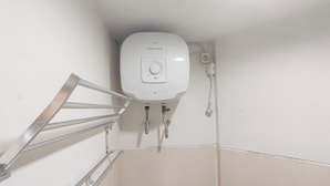 A corner of a bathroom with a white toilet, a metal handrail, and a wall-mounted heater. - Studio Minimalist And Warm At Pavilion Permata Apartment (Surabaya)