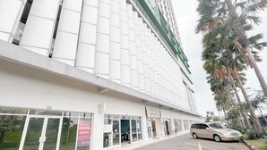 Un edificio moderno con fachada blanca y detalles verdes, con amplias ventanas y un estacionamiento que incluye un automóvil.