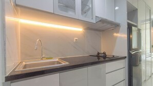 Una cocina moderna con un lavamanos de acero inoxidable, armarios blancos y una encimera negra.