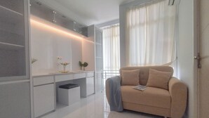 Una sala de estar moderna con un sofá color beige, un mueble blanco y una mesita con un florero.