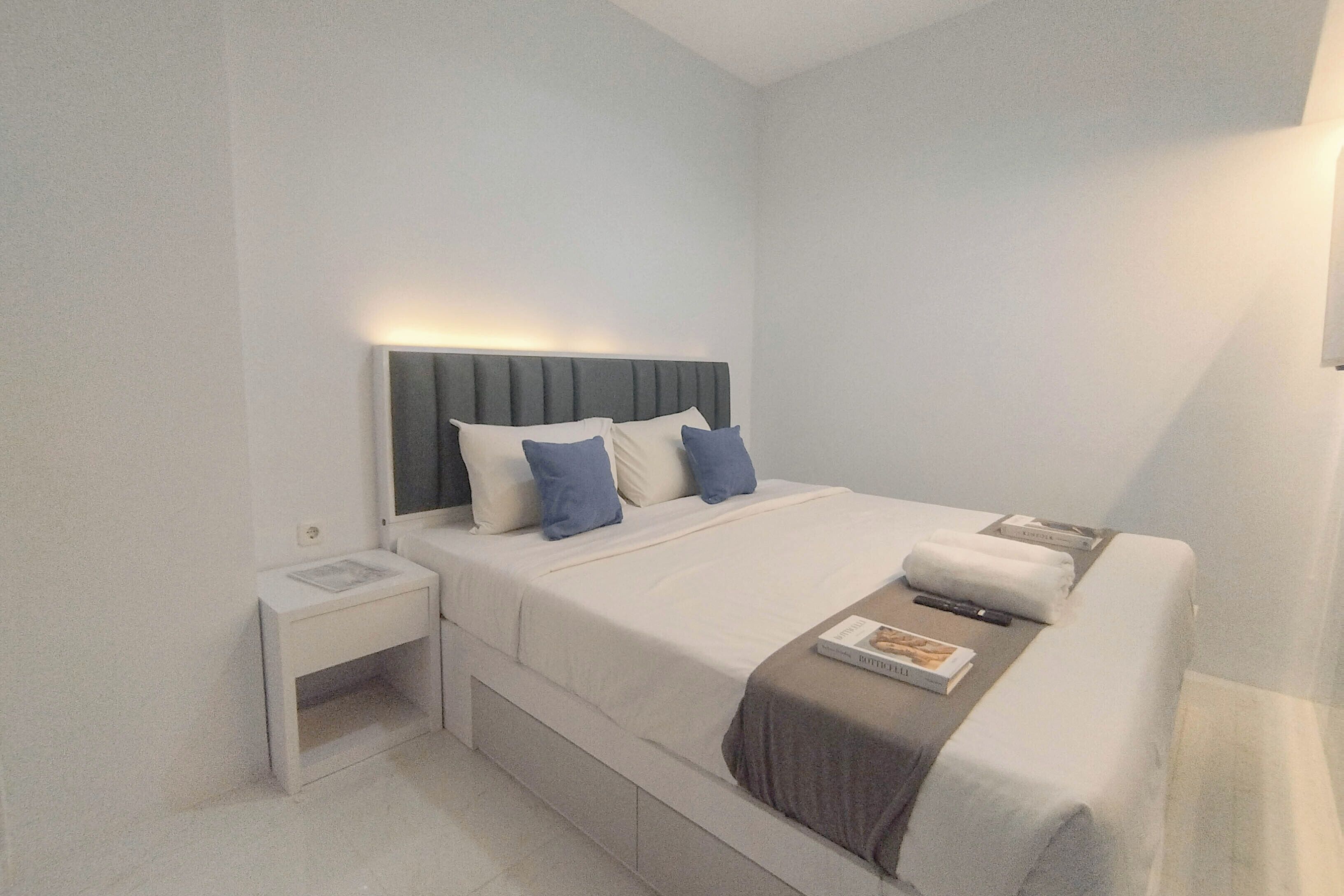 Ein modernes Hotelzimmer mit Bett, Nachttisch und einem kleinen Tisch daneben.