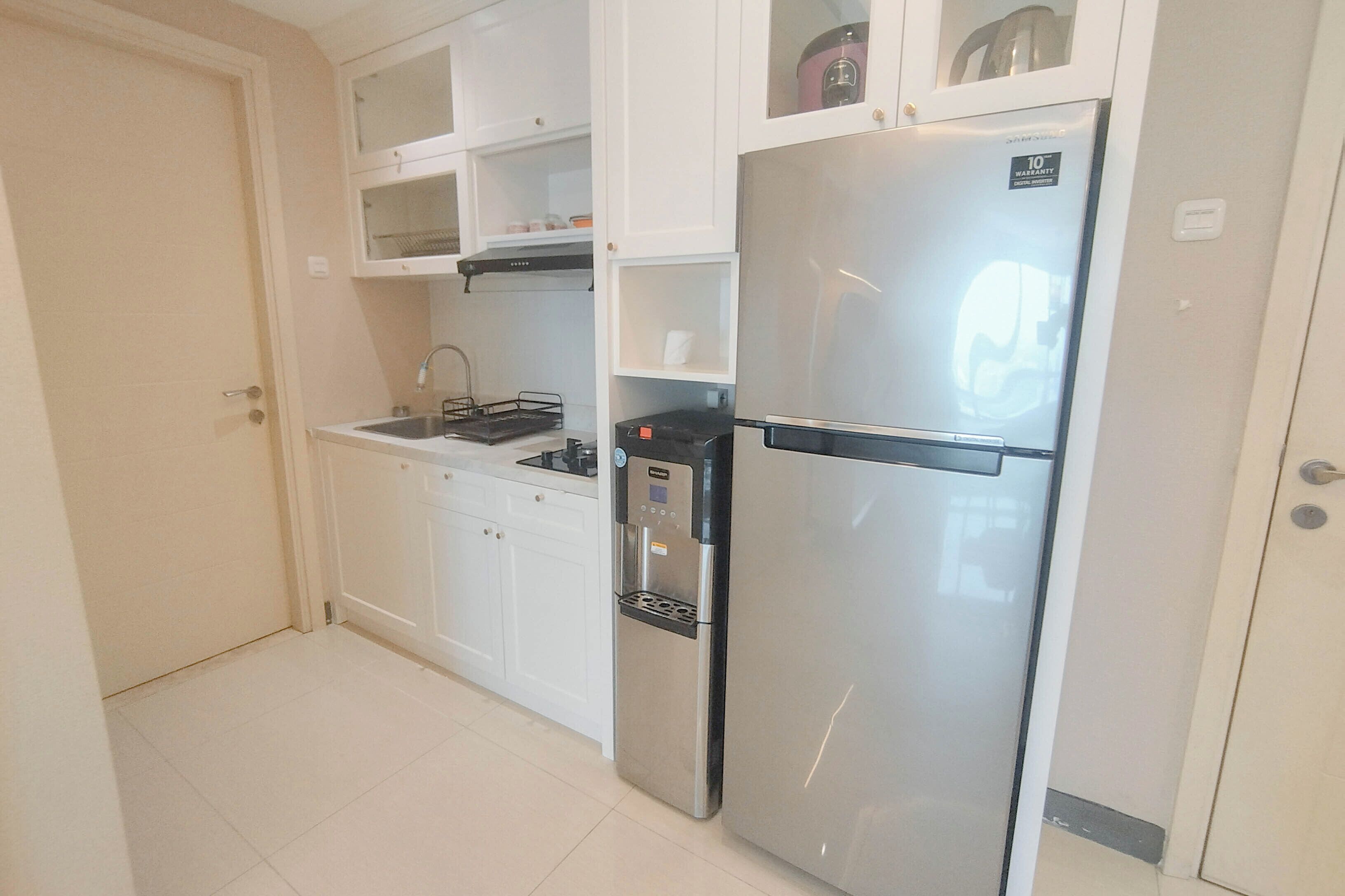 Una cocina con armarios blancos, un refrigerador de acero inoxidable, un horno empotrado y un lavamanos.
