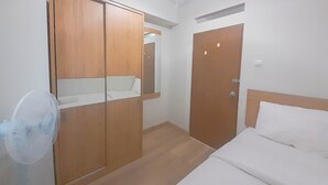 Un dormitorio con cama, armario de madera y ventilador.
