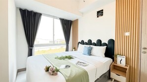A modern hotel room with a large bed, a window with curtains, a bedside table with a lamp, and a sign indicating the location as London. - 2Br Apartment At Tokyo Riverside Pik 2 Close To Tokyo Hub (Teluknaga)