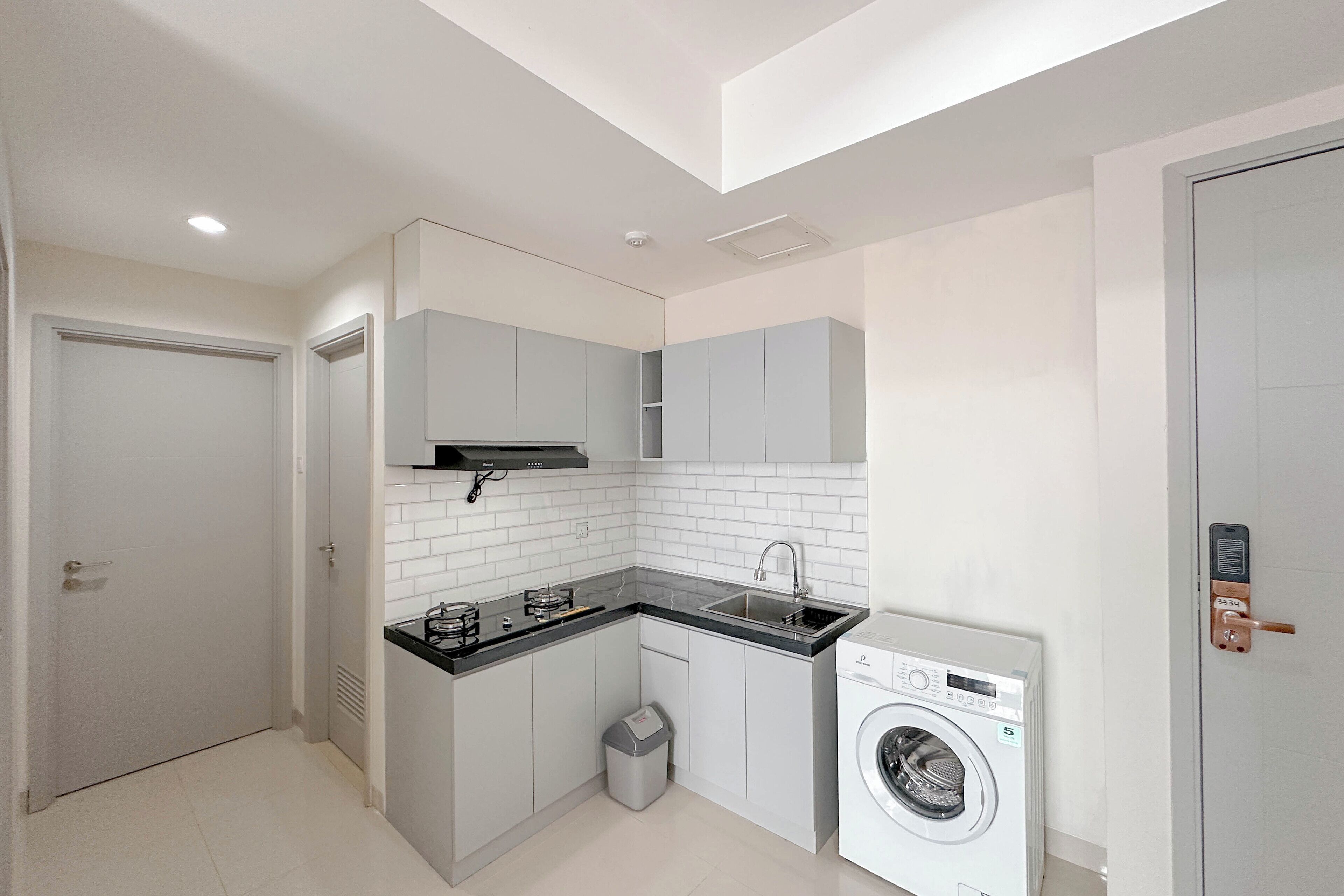 A compact kitchen with a washing machine, a sink, and cabinets.