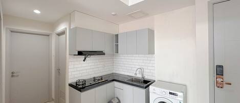 A compact kitchen with a washing machine, a sink, and cabinets.
