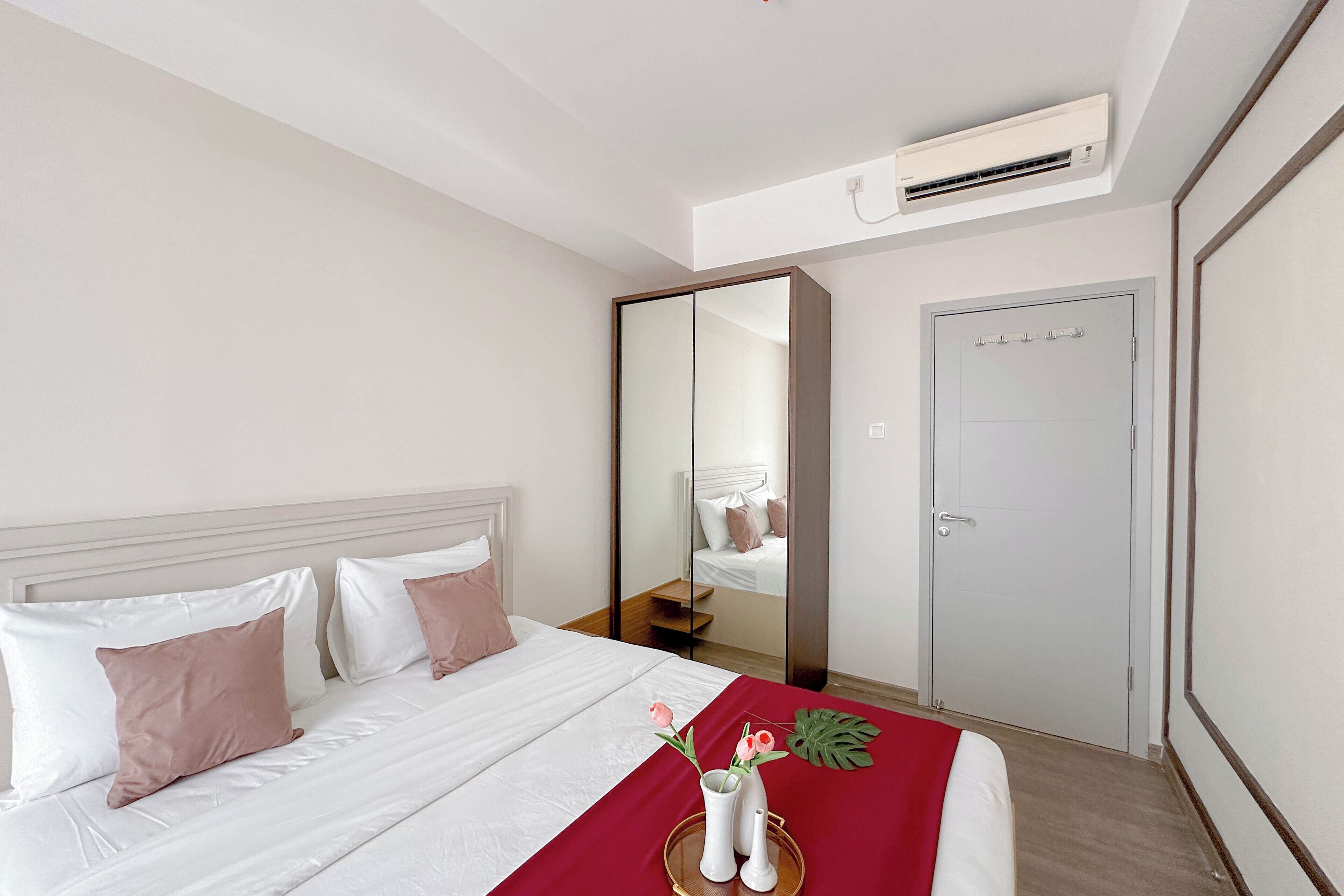 Una habitación de hotel con cama, espejo, armario y aire acondicionado.