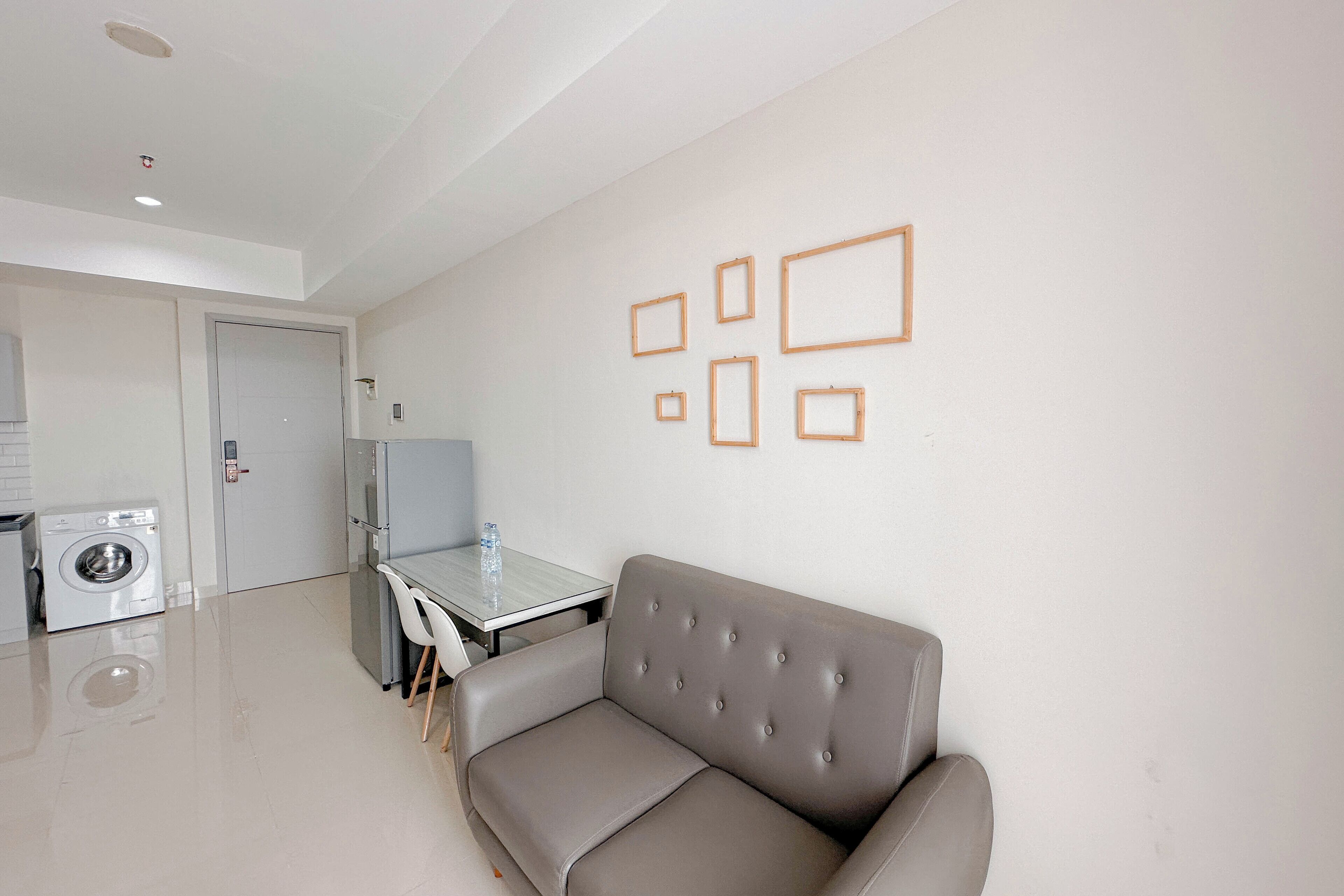 A modern living room with a grey sofa, a glass coffee table, and a wall with framed pictures.