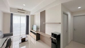 A modern living room with a sofa, a coffee table, a TV, and a refrigerator.
