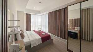 A modern hotel room with a large bed, a desk, and a mirror.