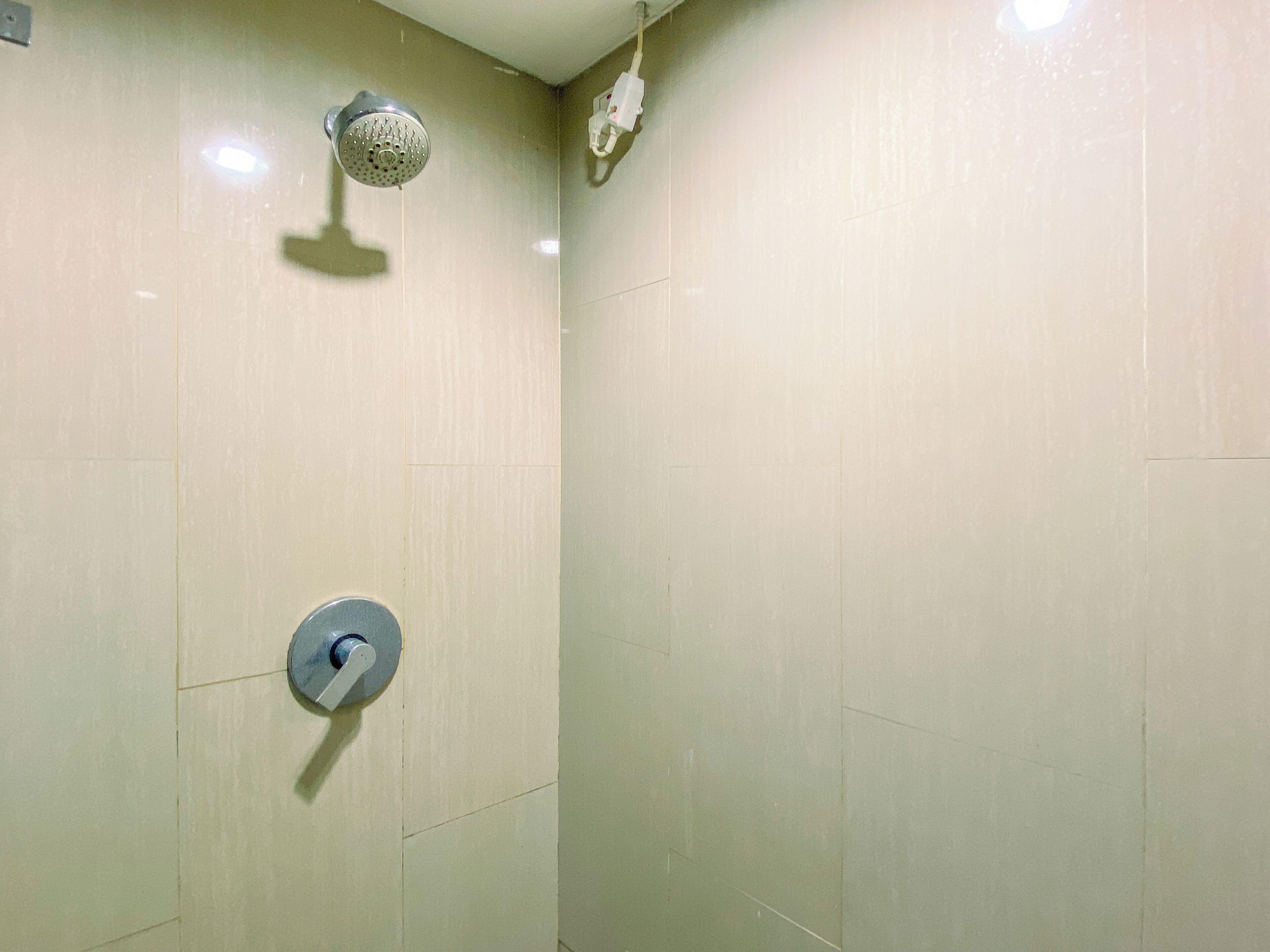 A shower with a handheld showerhead and a wall-mounted control valve.