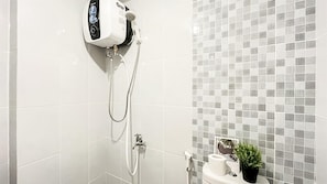 Un baño moderno con ducha, inodoro y un estante pequeño con artículos de aseo.