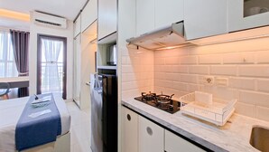 Une cuisine de taille réduite avec des meubles blancs, une cuisinière à gaz et un four encastré.