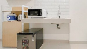 A compact kitchen with a microwave, sink, and a GE mini-fridge. - Studio (No Kitchen) Apartment At Bandaraya - Tallasa City Makassar Near Unhas (Makassar)