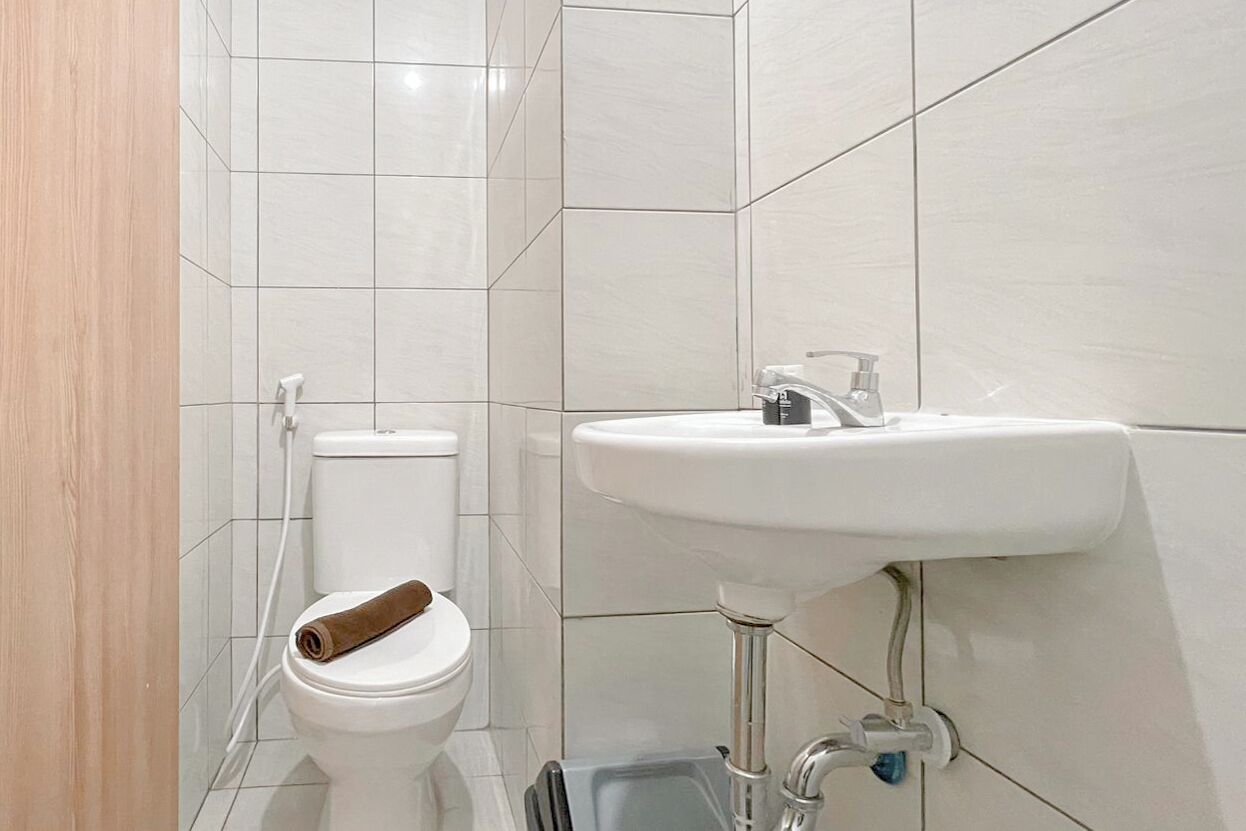 A bathroom with a toilet, a sink, and a towel on the toilet seat.