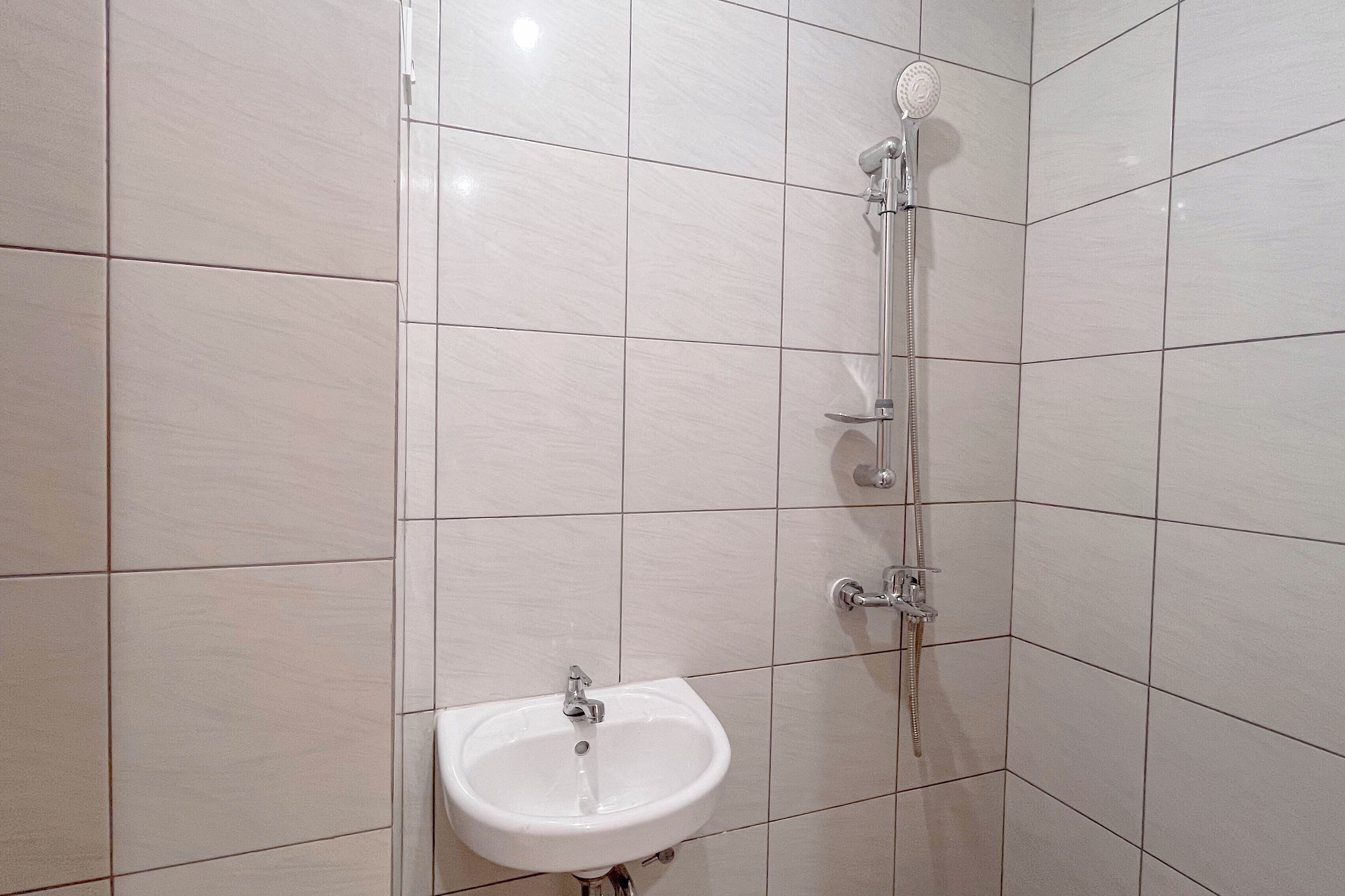 A bathroom with white tiles, a sink, and a shower.