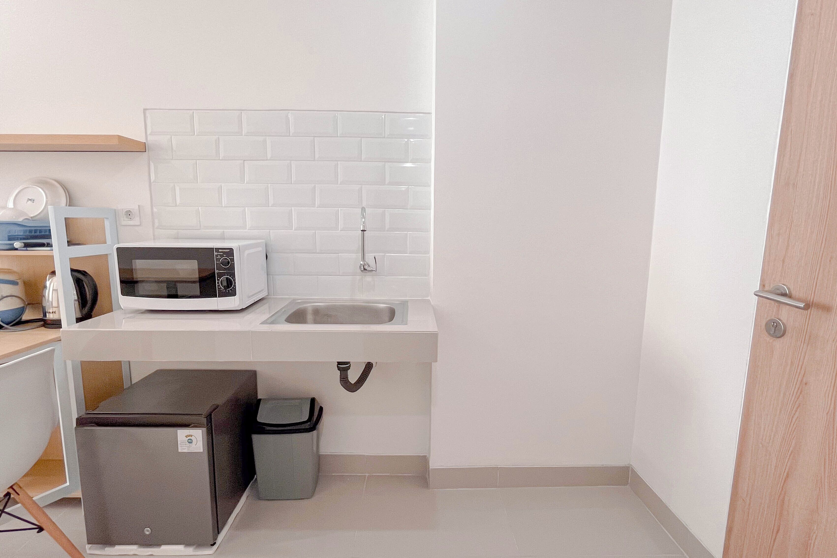 A compact kitchen with a microwave, sink, and storage cabinets.