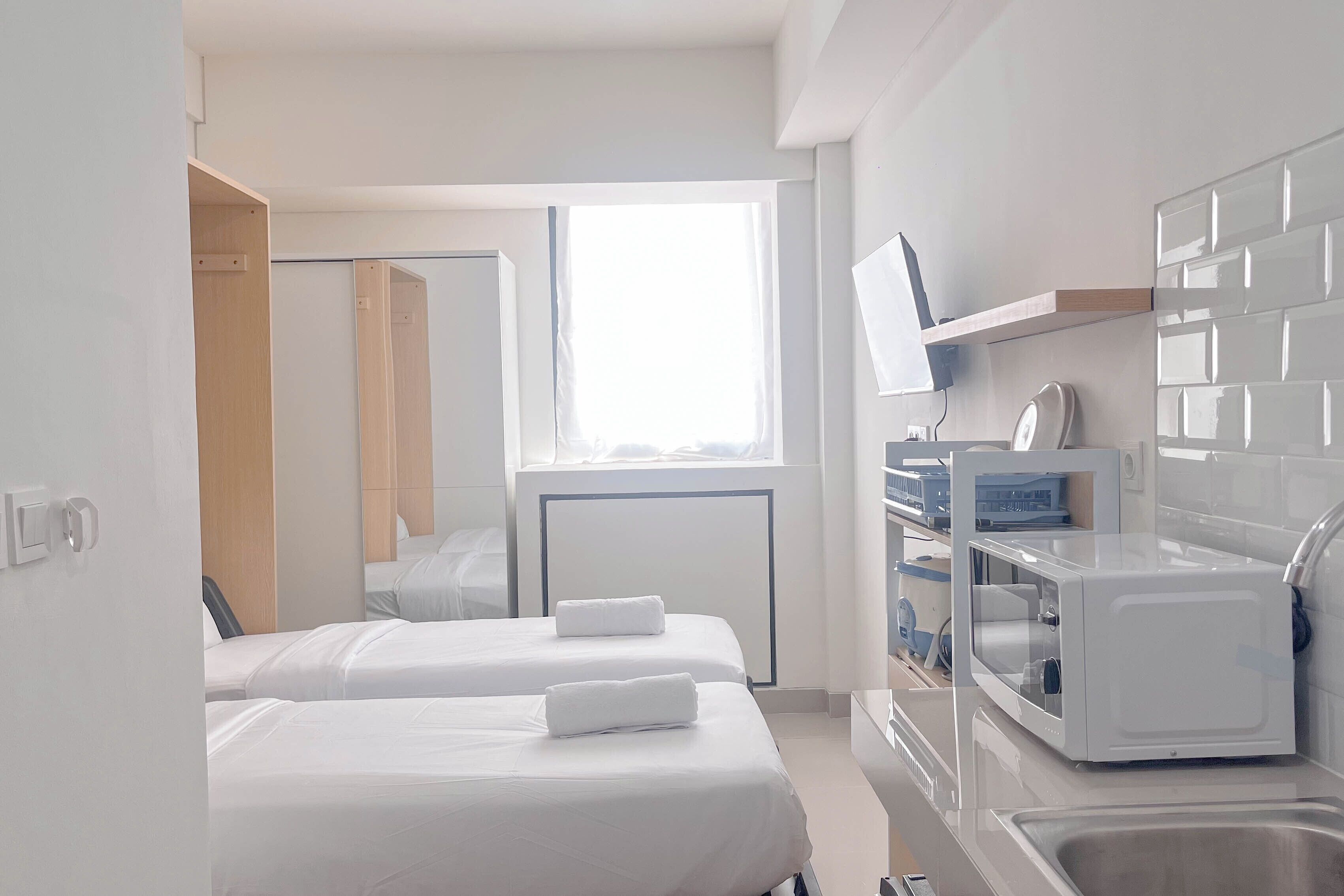 A hotel room with two beds, a TV, a microwave, and a sink.
