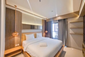 A modern hotel room with a large bed, built-in shelves, and a large window with curtains. - Warm And Minimalist Studio Apartment At Patraland Amarta (Ngaglik)