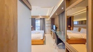 A modern hotel room with two beds, a desk, and a large mirror. - Warm And Minimalist Studio Apartment At Patraland Amarta (Ngaglik)