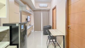A compact kitchen with a refrigerator, a small table, and a chair. - Simple Style 2Br Apartment Vida View Makassar (Makassar)