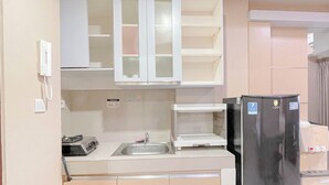 A compact kitchen with a refrigerator, sink, and cabinets. - Simple Style 2Br Apartment Vida View Makassar (Makassar)