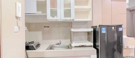 A compact kitchen with a refrigerator, sink, and cabinets.