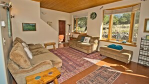 A cozy living room with a wooden ceiling, a large window with a view of the outdoors, and a rug on the floor. - White Lotus House - 2 BR, 2.5 Bath Luxury Sanctuary in Crestone, Colorado (Crestone)