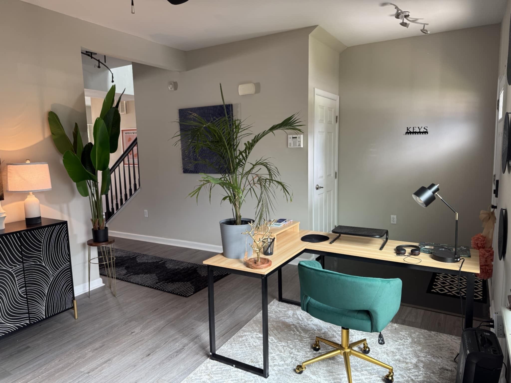 Una sala de estar moderna con un escritorio de madera, una silla color turquesa y una escalera que sube a otro nivel.