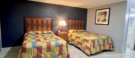 Una camera d'albergo con due letti, un comodino, una lampada e un quadro appeso al muro.
