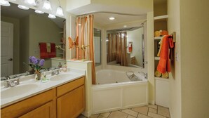 Une salle de bain avec un double lavabo, une baignoire et un rideau de douche.