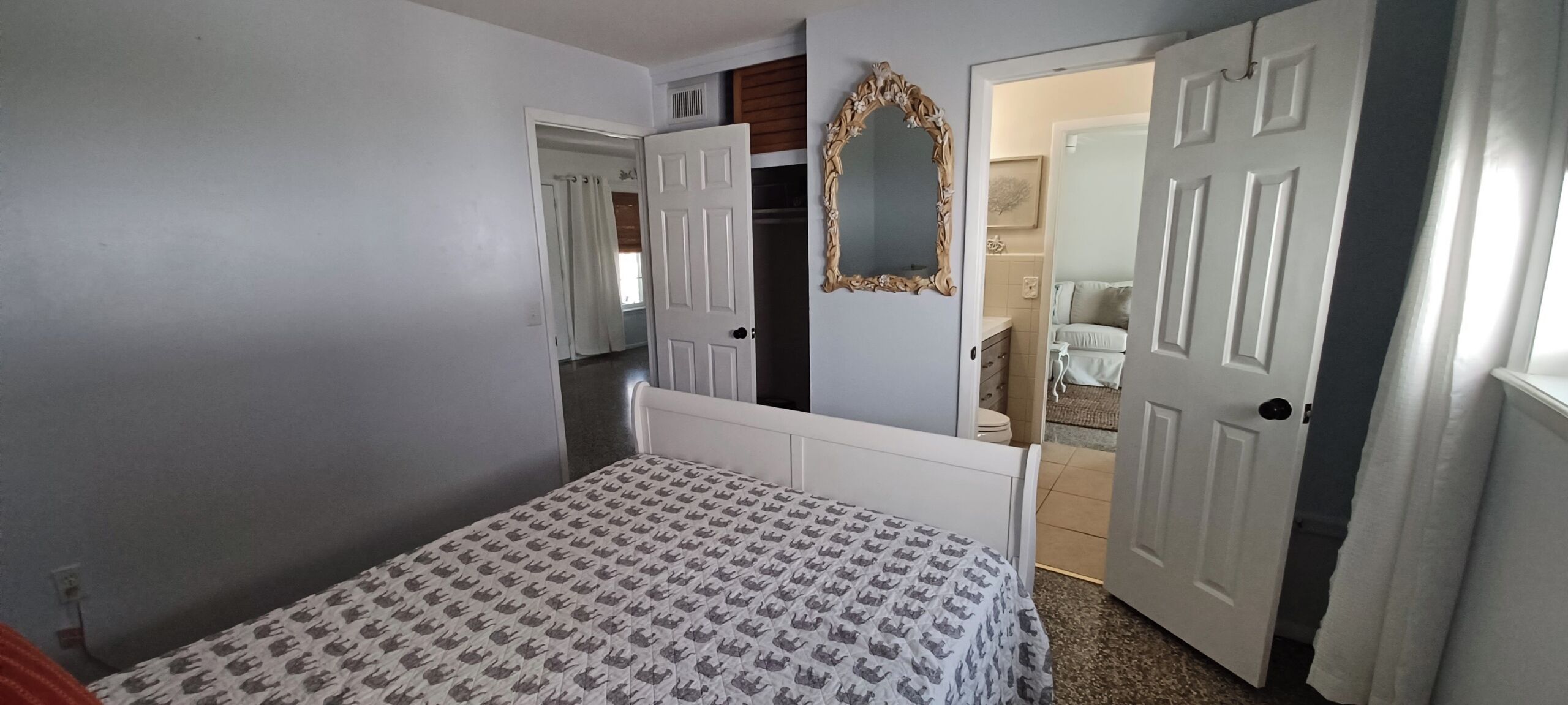Une chambre à coucher avec un lit, un miroir et deux portes donnant sur d’autres pièces.