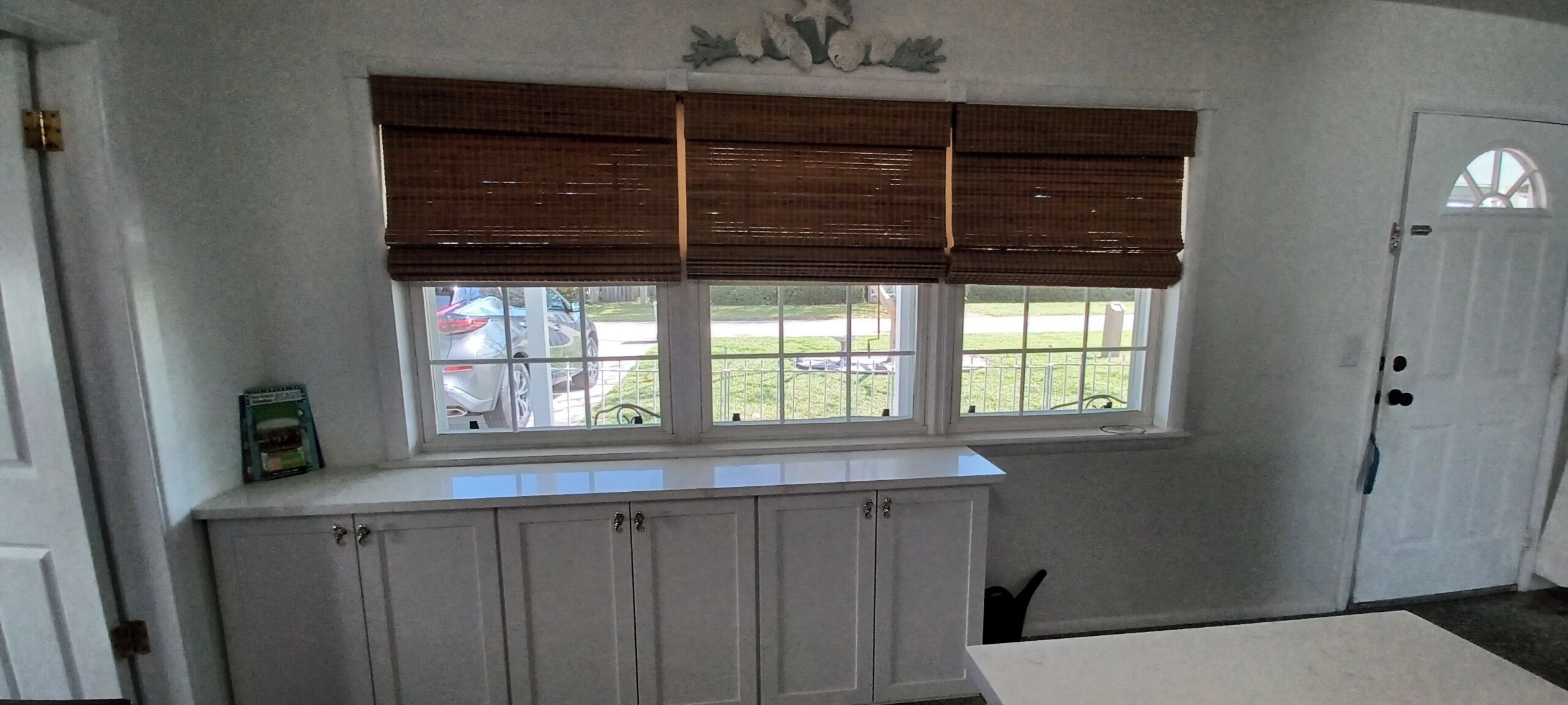 A kitchen with a window, white cabinets, and a door.
