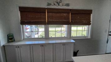 A kitchen with a window, white cabinets, and a door.