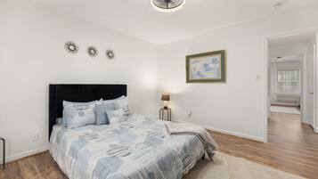 Een slaapkamer met een bed, nachtkastje, lamp en plafondventilator.