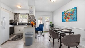 Una cocina moderna con armarios blancos, encimera negra y una silla azul.