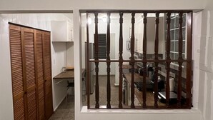 A room with a wooden closet, a kitchen area with cabinets, and a window with a barred view. - Marvelous 3-2 house for 6 Big/affordable in Aguadilla (Aguadilla)
