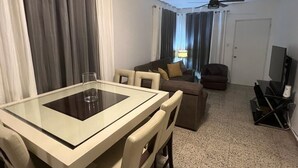 A hotel room with a dining table, a sofa, a TV, and a ceiling fan. - Marvelous 3-2 house for 6 Big/affordable in Aguadilla (Aguadilla)