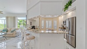 A modern kitchen with a central island, white cabinetry, and stainless steel appliances. - Ft. Myers Beach Escape | Pool + Canal Views (Fort Myers Beach)