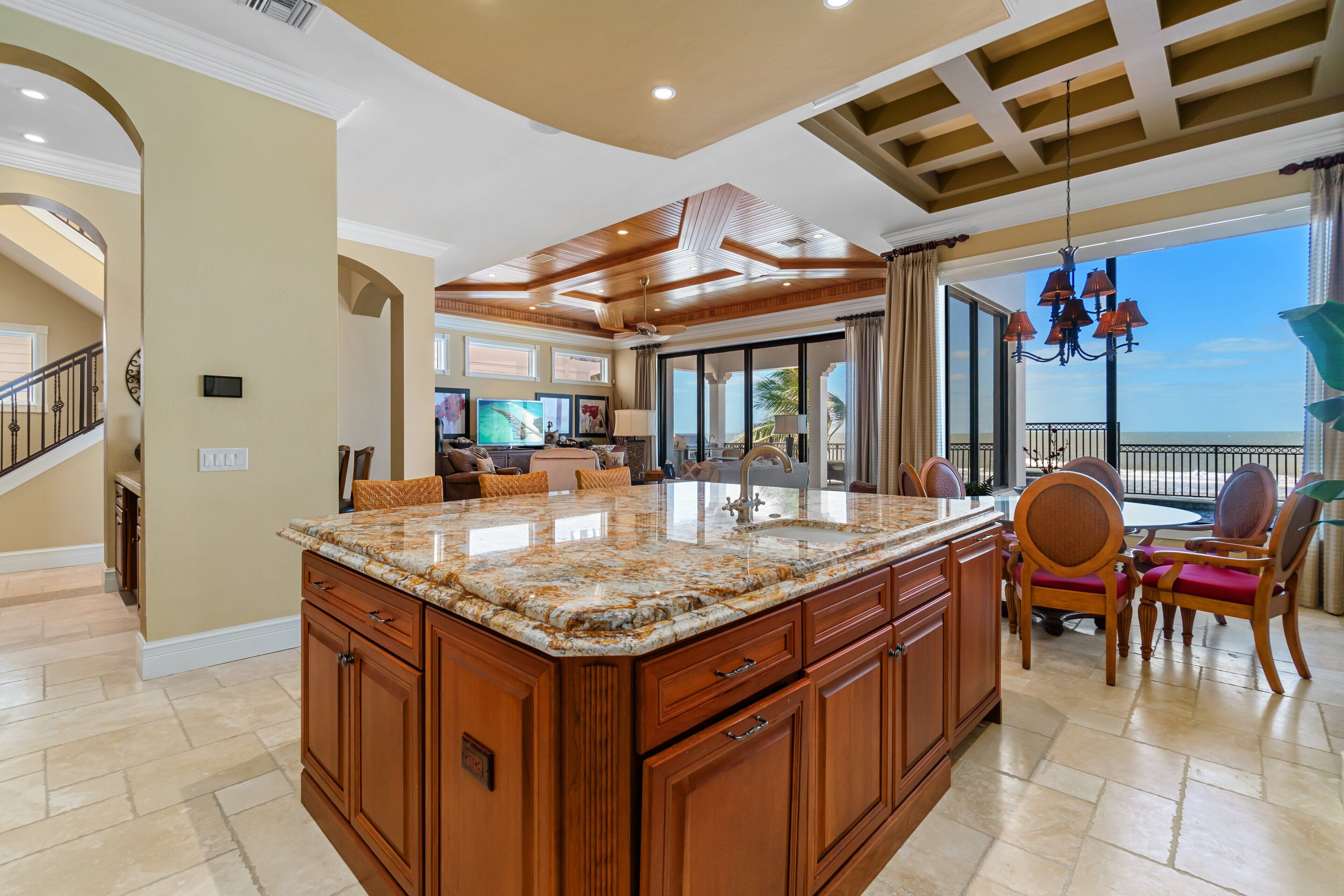 A spacious kitchen with a large island, wooden cabinets, and a view to the outside.