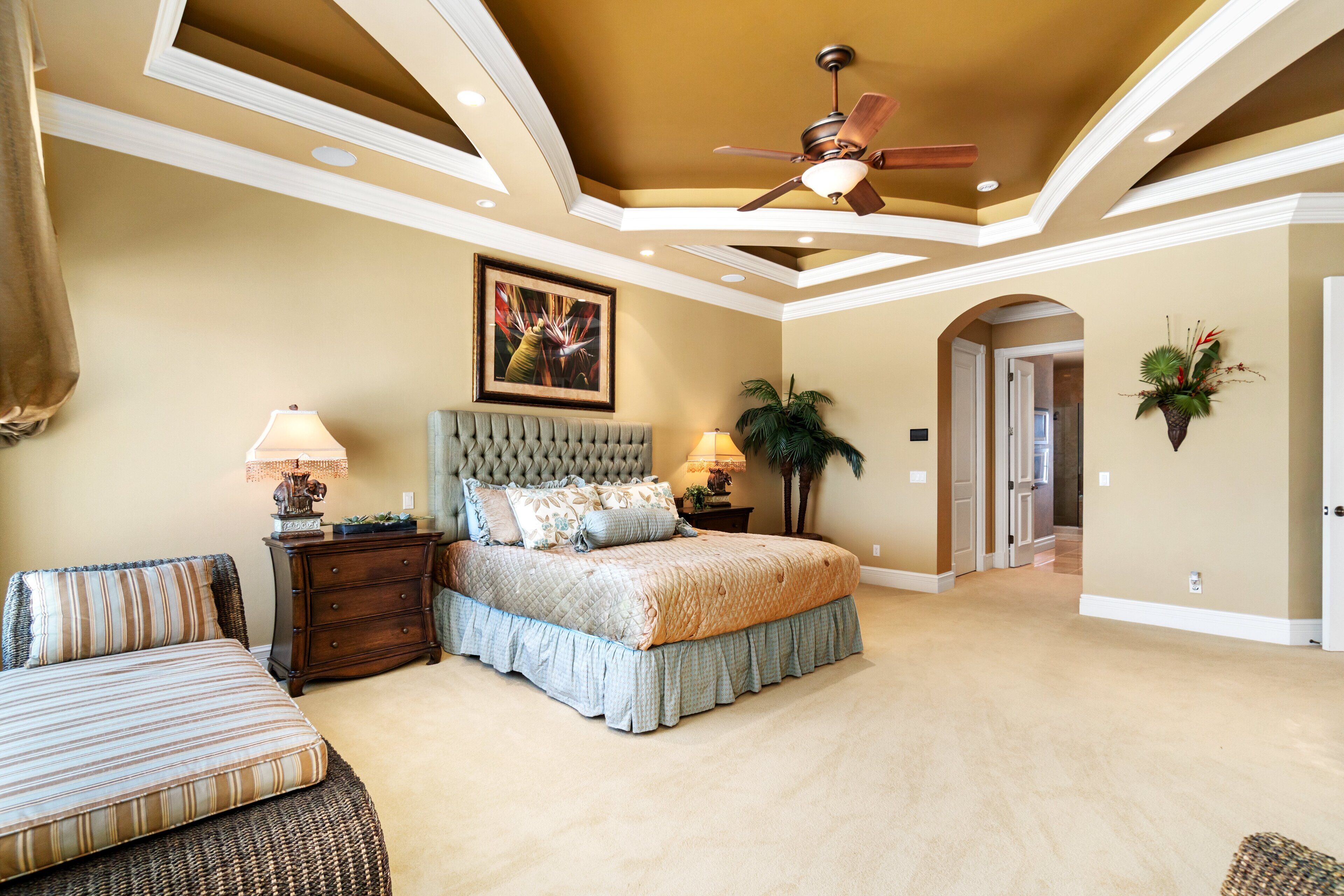 Quarto com uma cama grande, um ventilador de teto e um quadro na parede.