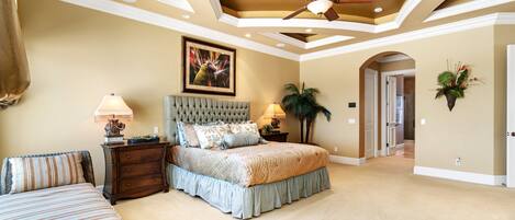 Quarto com uma cama grande, um ventilador de teto e um quadro na parede.