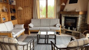 A cozy living room with a sofa, chairs, a coffee table, and a fireplace. - Nice new chalet for rent in Les Collons (Vex)