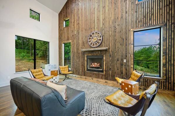 Una sala de estar moderna con chimenea, ventanas amplias y vistas a zonas verdes.