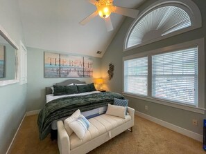A bedroom with a bed, a ceiling fan, a window with blinds, a wall-mounted artwork, and a light fixture. - Pet Friendly 4 Bedroom Just Steps to Beach (Cape May Point)