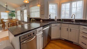 A modern kitchen with white cabinets, a granite countertop, and a dishwasher. - Pet Friendly 4 Bedroom Just Steps to Beach (Cape May Point)