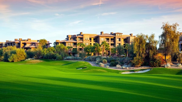 A golf course with a clubhouse and residential buildings in the background.