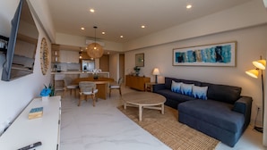 A modern living room with a dark blue sofa, a round coffee table, and a dining area with a wooden table and chairs. - Mar del Plata 5B (Bucerías)