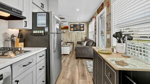 Una cocina moderna con armarios blancos, un refrigerador de acero inoxidable y una zona de comedor de madera.