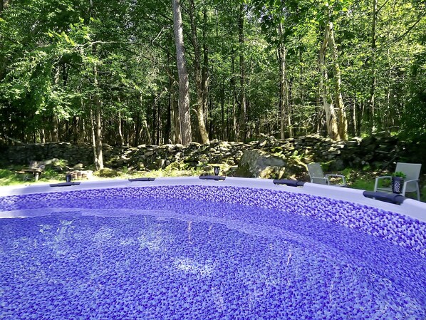 A swimming pool surrounded by trees and a stone wall.